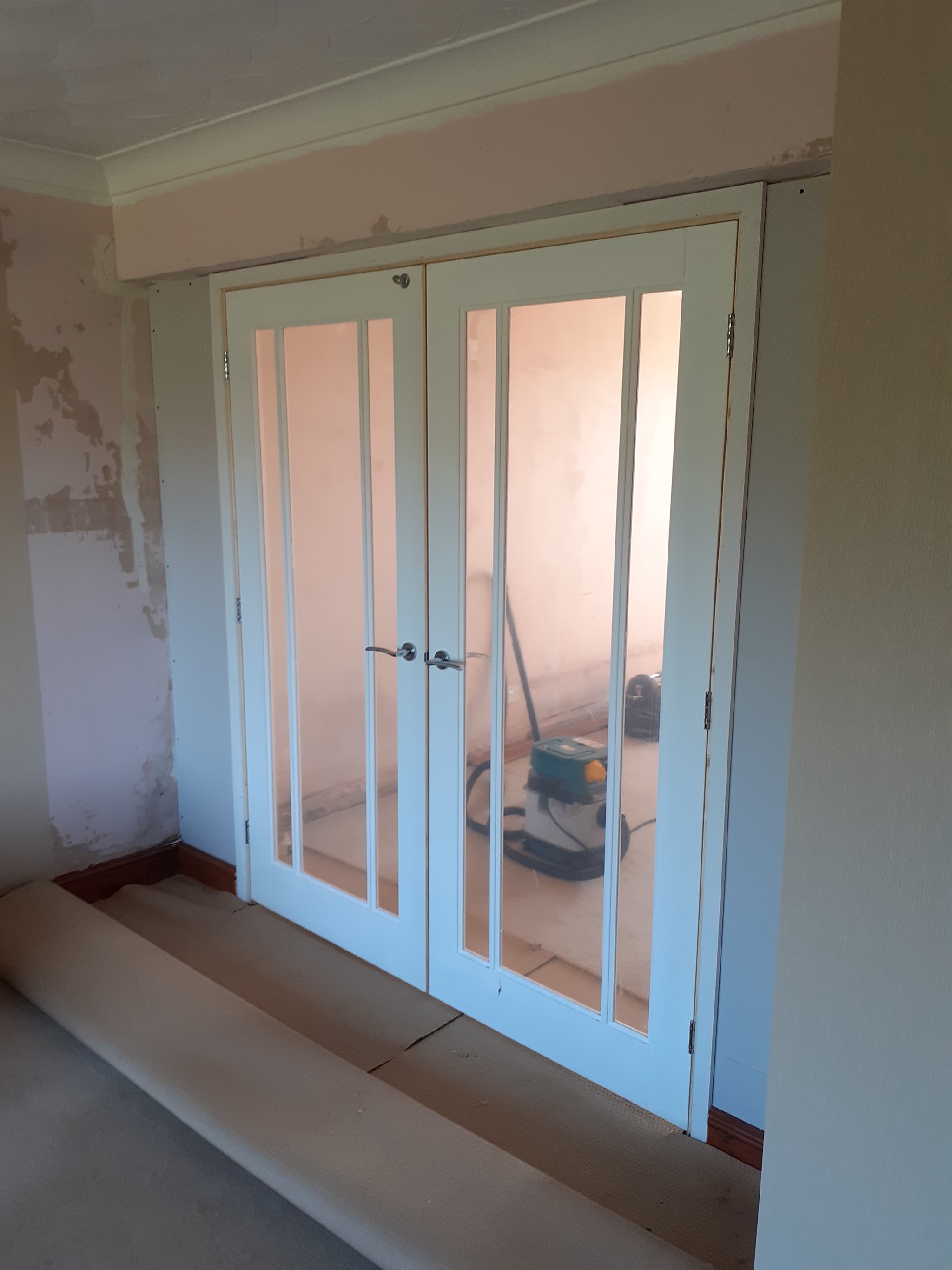 White glazed double doors fitted in a room mid-renovation